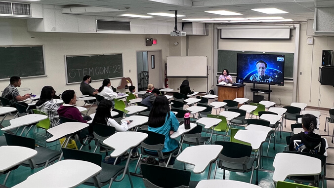 people sitting in a class looking at a screen