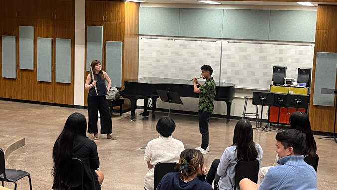 person with a flute performing in front of an audience