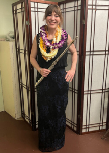 person holding a flute with lei on