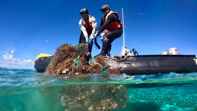 people pulling marine debris out of water