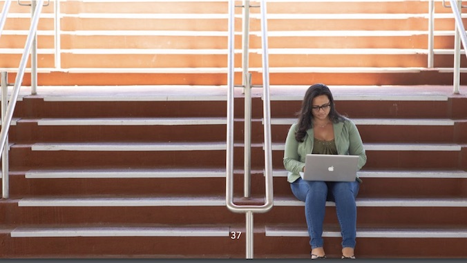 student sitting on steps and working on her laptop
