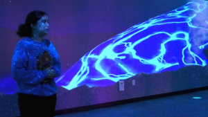 Person standing next to a glowing blue digital projection