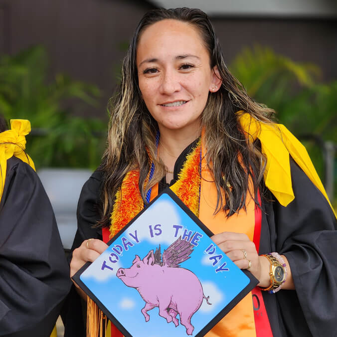 Graduate holding her cap with the words "today is the day" with a picture of a flying pig