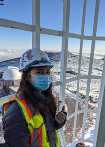 person smiling with a mask at the top of a mountain