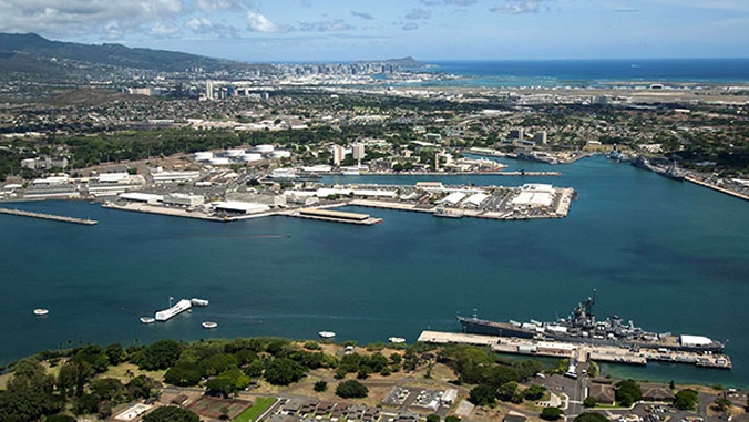 aerial shot of pearl harbor with the ocean, land, buildings and ships