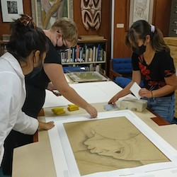 students working with preservation specialist on charlot print