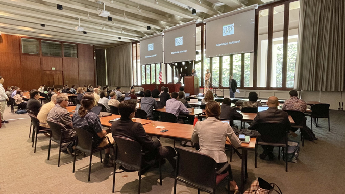 people sitting in a room with large screens