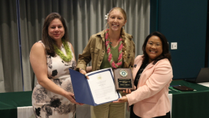 three people smiling holding up awards