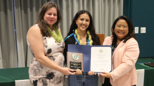 three people smiling holding up awards