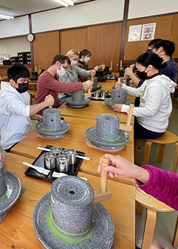 students grinding tea with stones