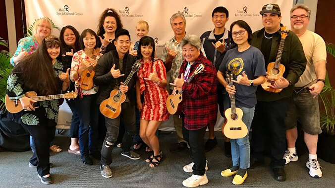 Group of people smiling, holding ukulele