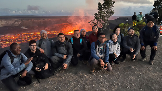 Group of people in front of the actively erupting volcano