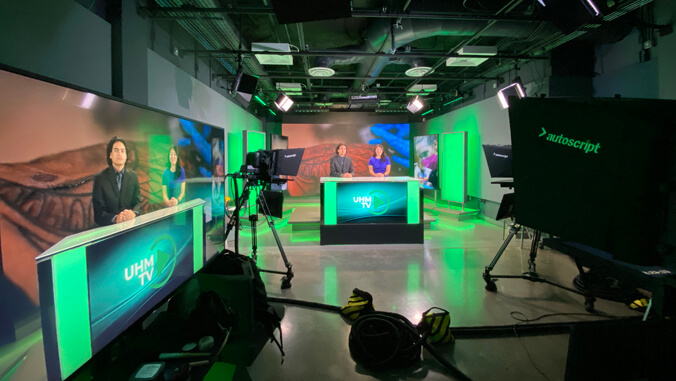 two people on a desk with cameras and televisions