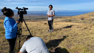 person standing in front of the camera with two people behind the camera