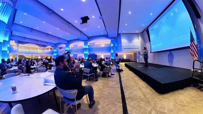 person standing on a stage talking to a large audience