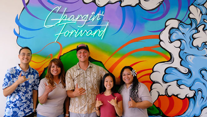 five people smiling with shakas 