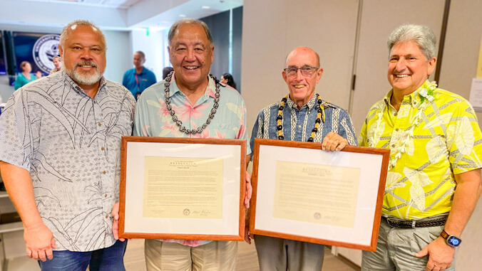 Four people, two are holding their framed proclamations