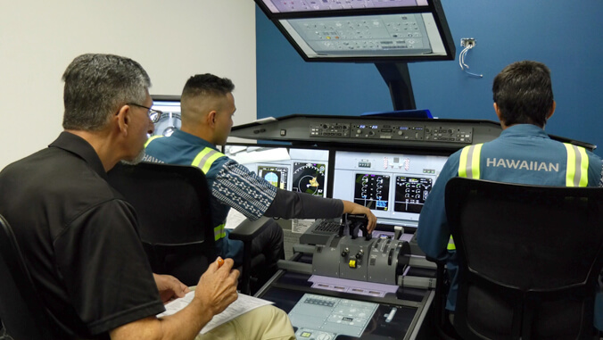 Three people sitting in a training control console