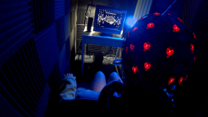 person wearing a device with red lights sitting in front of a computer