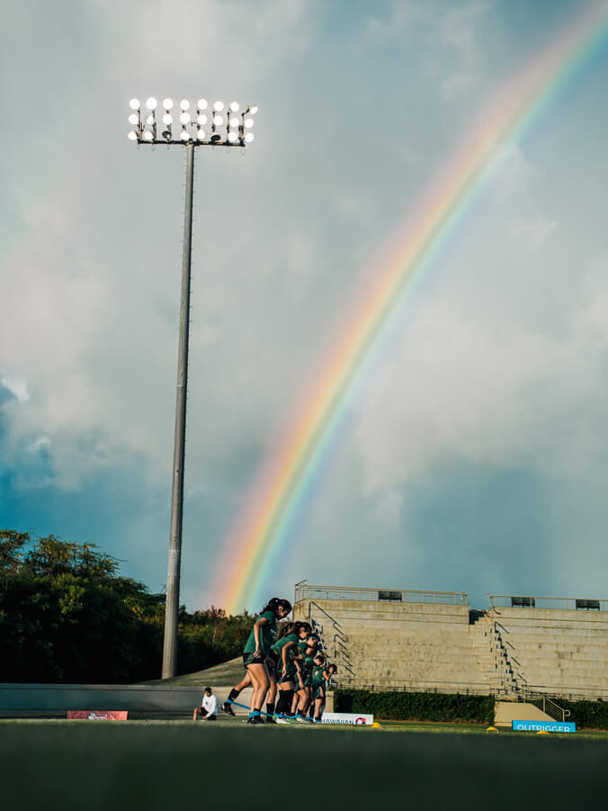 Wahine Soccer players practicing under a rainbow