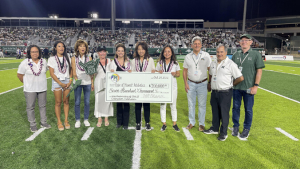 People standing on the football field holding a check
