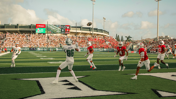 person in a white jersey catching a football in the endzone