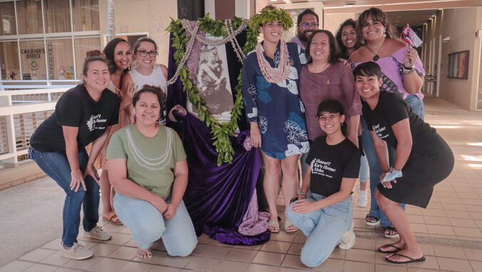 U H N H S S students and faculty with lei draped portrait of Liliuokalani