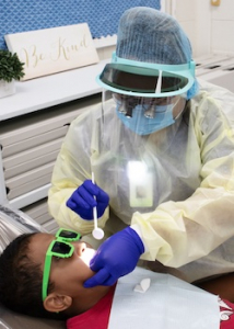 dental hygienist applies dental sealant to studentʻs teeth