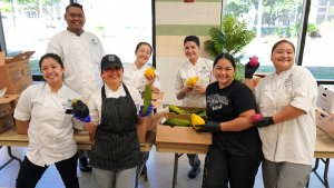 people posing with boxes of fruits and vegetables