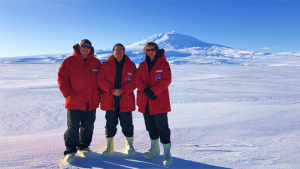 three people standing in a vast landscape of ice