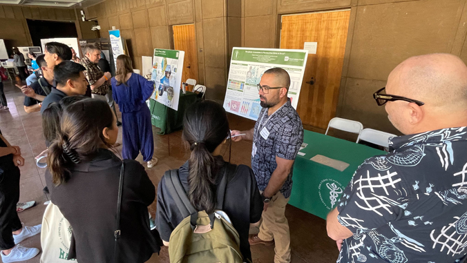 people speaking to each other near a large poster board