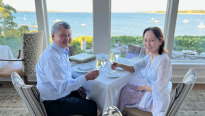 Two people seated at a table holding glasses of champagne