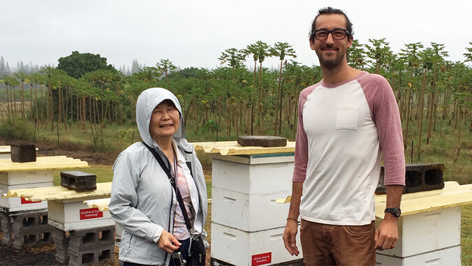 Two people standing with beehives