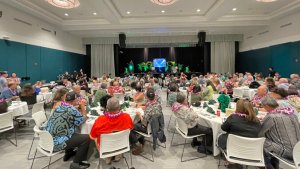 people sitting in chairs in a large ballroom