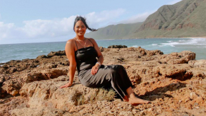 person sitting on rocks by the ocean