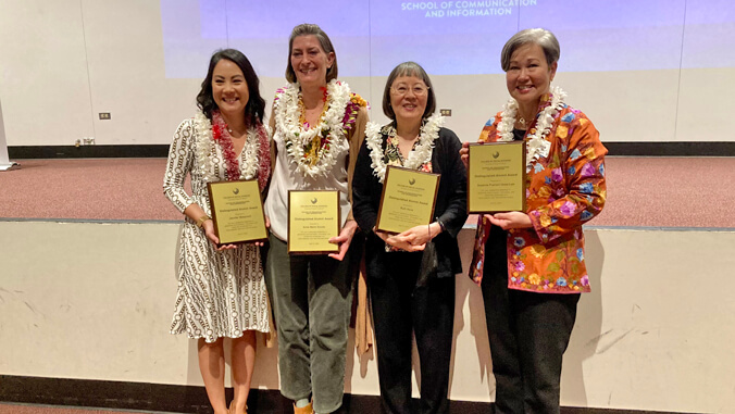 four people standing and smiling with awards