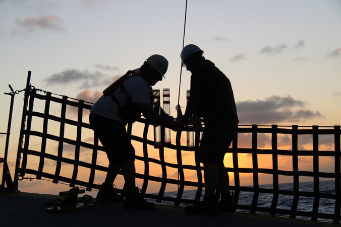 Silhouettes of two people on a research ship