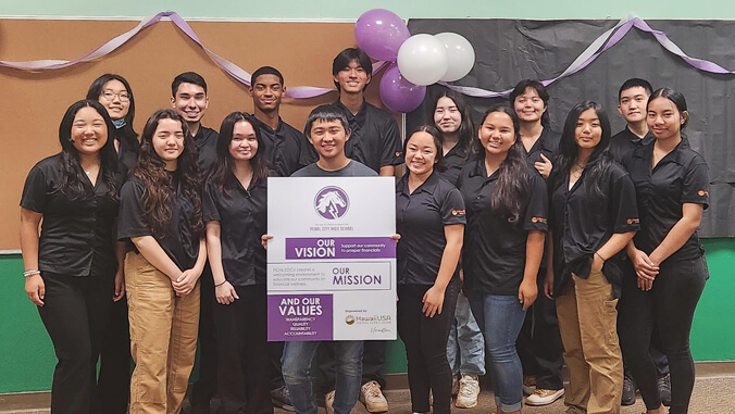 a group photo of students holding a board