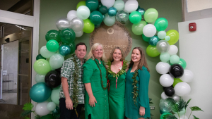 four people smiling in front of a bunch of balloons