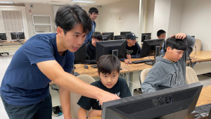 person pointing to a computer screen while others look on