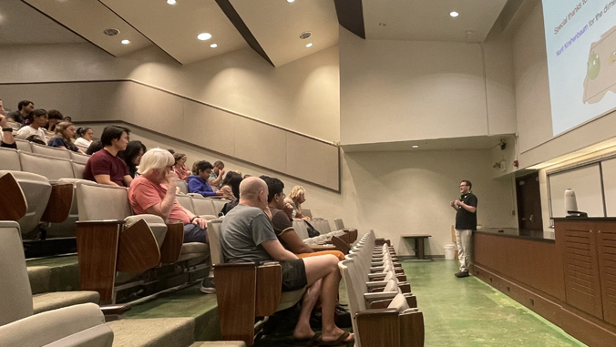 person speaking to a large group in a lecture hall