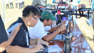 people looking at a computer with a large drone next to it