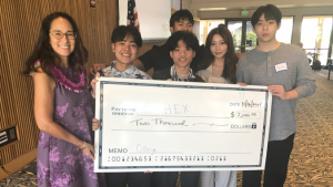group of people standing and holding a large check