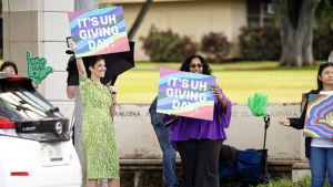 Smiling people holding It's Giving Day signs