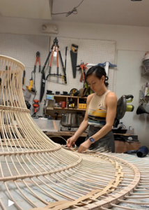 Person working on a open weave conical shape