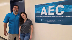 Two people in front of an A E C sign
