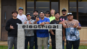 Group of smiling students in front of a sign
