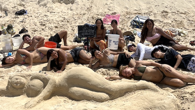 architecture students pose with sand castle design of Te Fiti from Moana