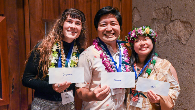 Three smiling people holding envelopes