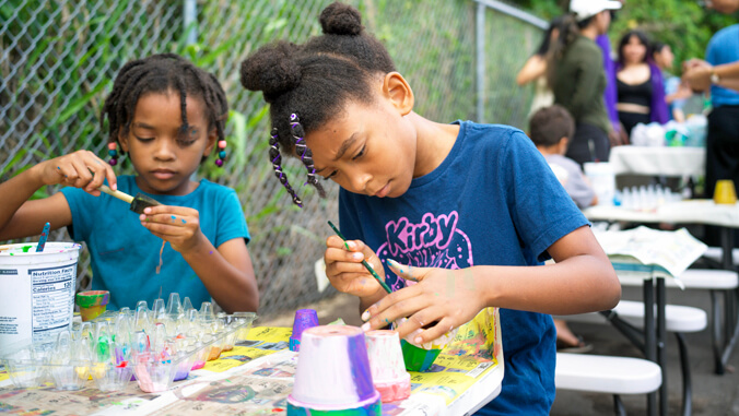 2 girls painting a plant pot